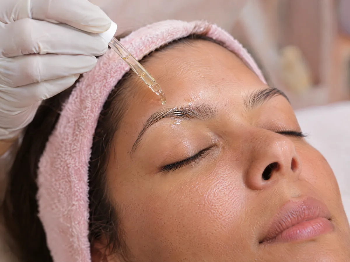 Profissional aplicando ativos na sobrancelha de uma cliente relaxada